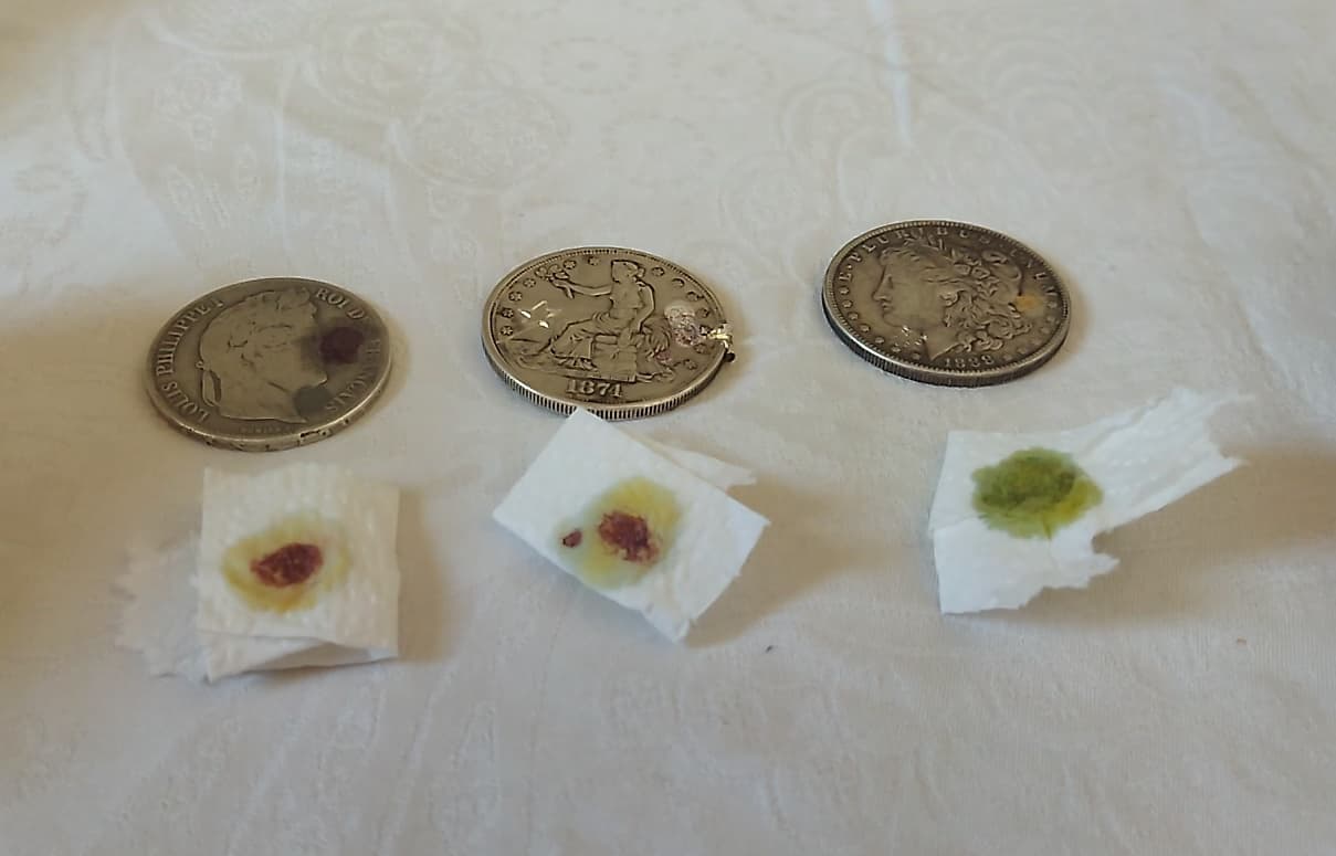 Acid test residue on paper: red-brown for silver-rich coins, green for the base-metal fake