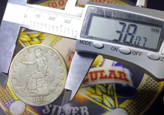 Digital caliper reading the fake Trade Dollar's diameter at 38 mm