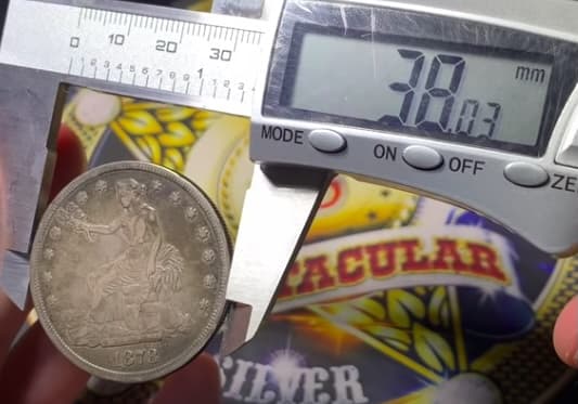 Digital caliper reading a genuine Trade Dollar's diameter at 38 mm