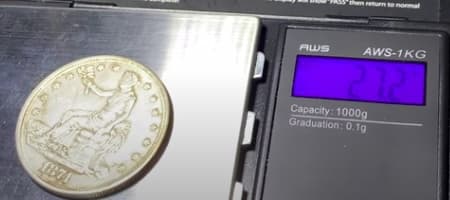 Digital scale reading the fake Trade Dollar at 27.2 g